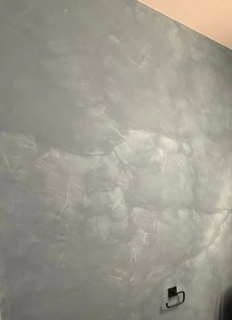 A close view of burnished plaster: knife facets and a soft sweep of sheen across the surface